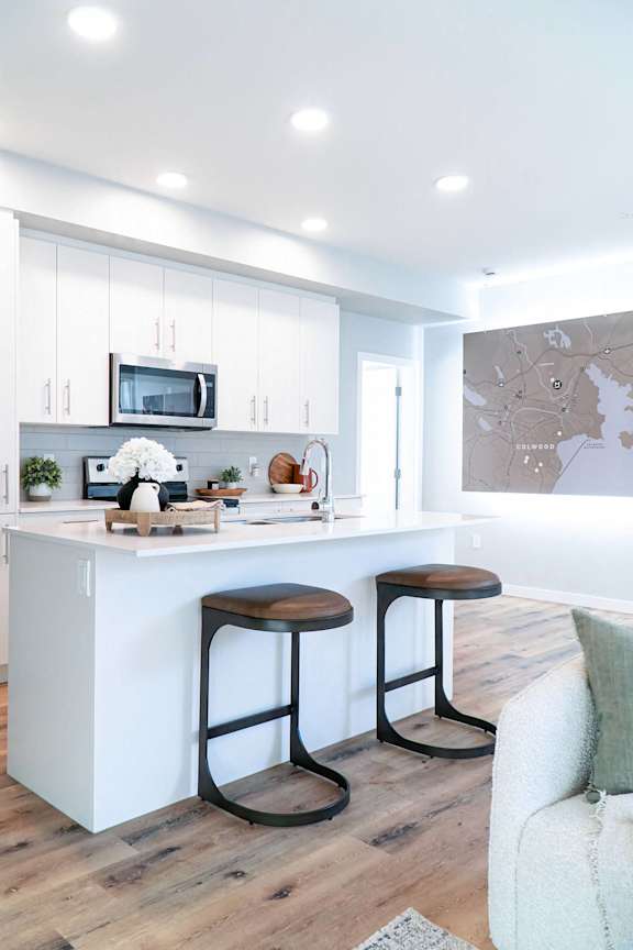 A kitchen with a white island and two stools.