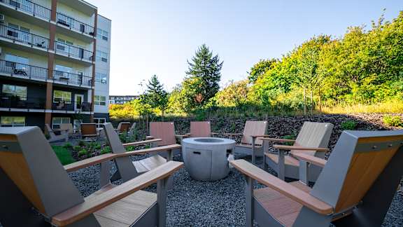 A modern outdoor seating area with wooden benches and a fire pit.