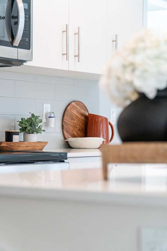 A kitchen counter with a microwave, a plant, and a vase with flowers.