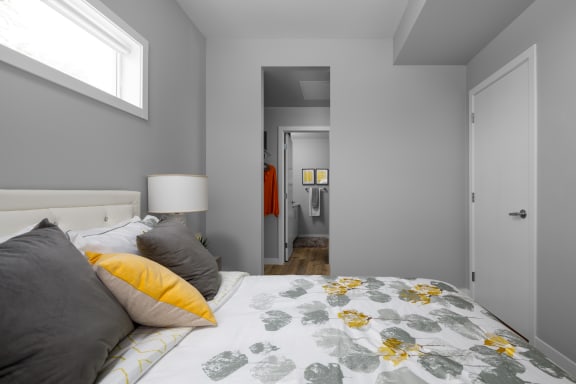 a bedroom with gray walls and a bed with gray and yellow pillows