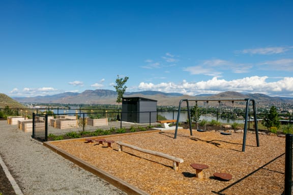 a playground with a view of the water and mountains in the background