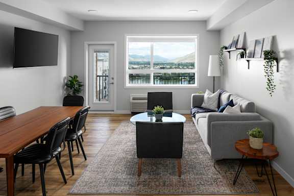 A living room with a couch, chairs, a coffee table, and a flat-screen TV.