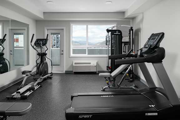 A black and white photo of a gym with a treadmill in the foreground.