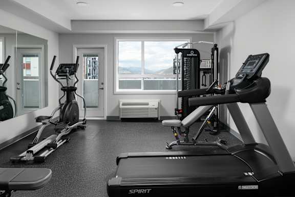 A black and white photo of a gym with a treadmill in the foreground.