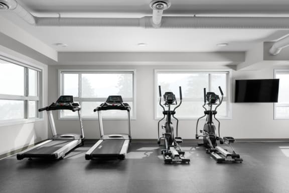 four treadmills in a room with windows and a television