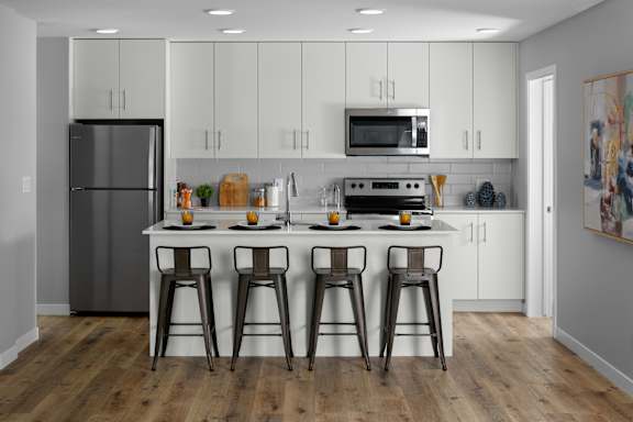 A kitchen with white cabinets and a wooden floor.