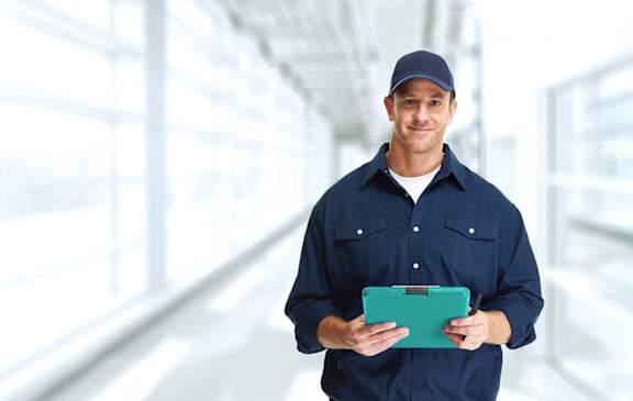 A man in a blue shirt and cap holding a tablet.