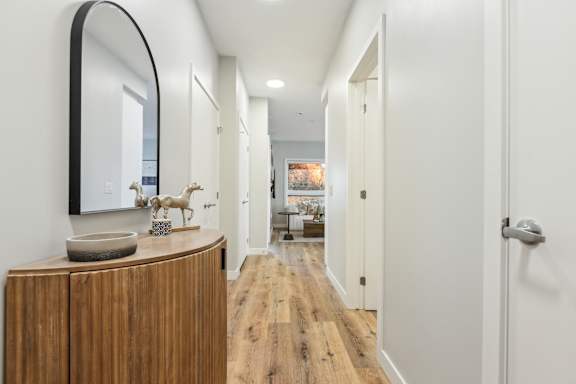 A hallway with a wooden floor and white walls.