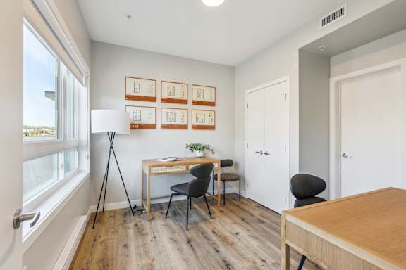 A room with a desk, chairs, and pictures on the wall.