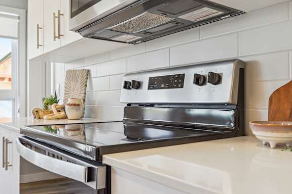 A modern kitchen with a stainless steel oven and white countertops.