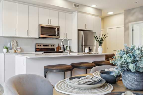 A modern kitchen with white cabinets and a breakfast table set.