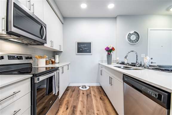 A modern kitchen with a wooden floor and stainless steel appliances.