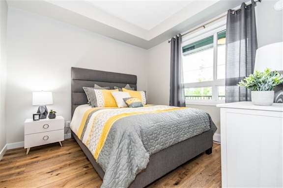 A bedroom with a large bed and a nightstand with a lamp.