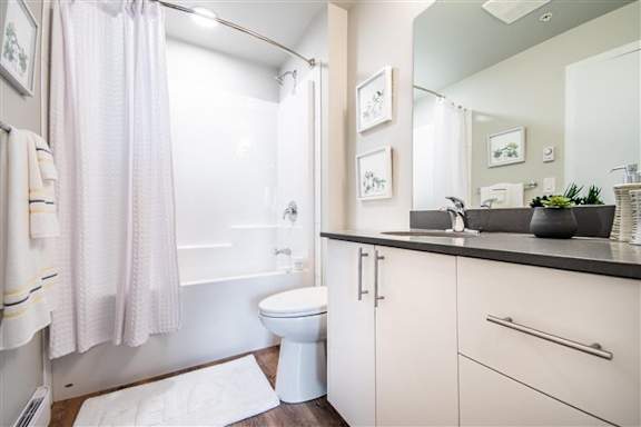 A bathroom with a white toilet, a sink, and a shower with a pink curtain.