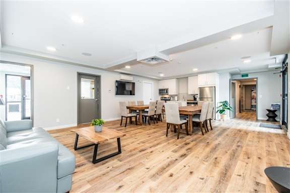 A spacious living room with a grey sofa and a wooden dining table.