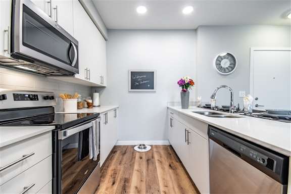 A modern kitchen with stainless steel appliances and wooden floors.