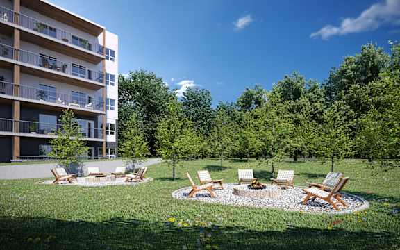 A modern apartment building with a lush green lawn and outdoor furniture.