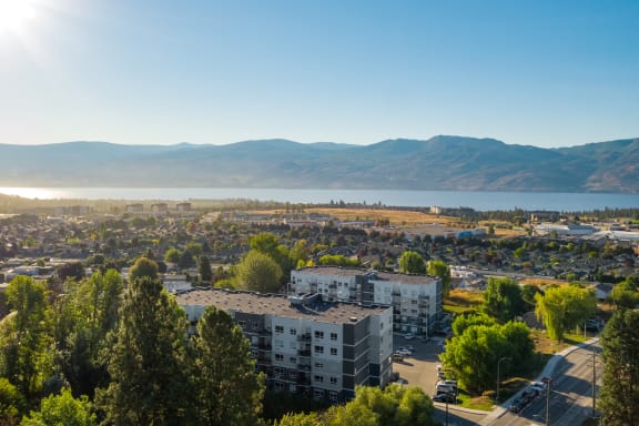 an aerial view of a city with a lake and mountains in the background