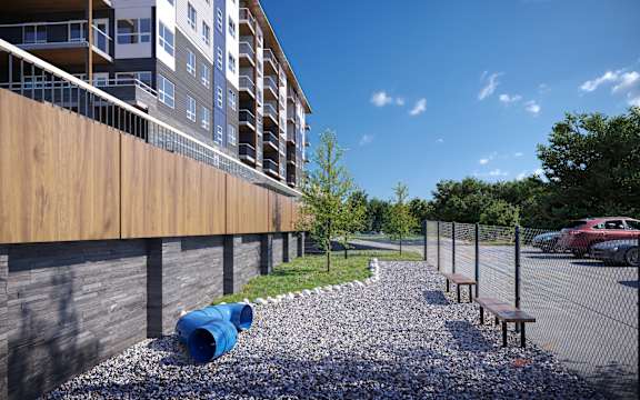 A modern building with a wooden fence and a gravel area with benches.