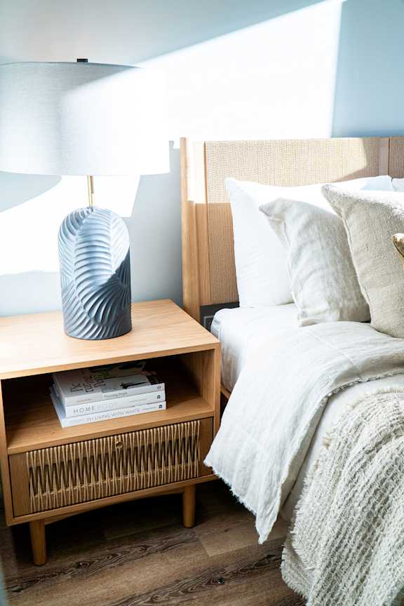 A bedroom with a bed, nightstand, and lamp.