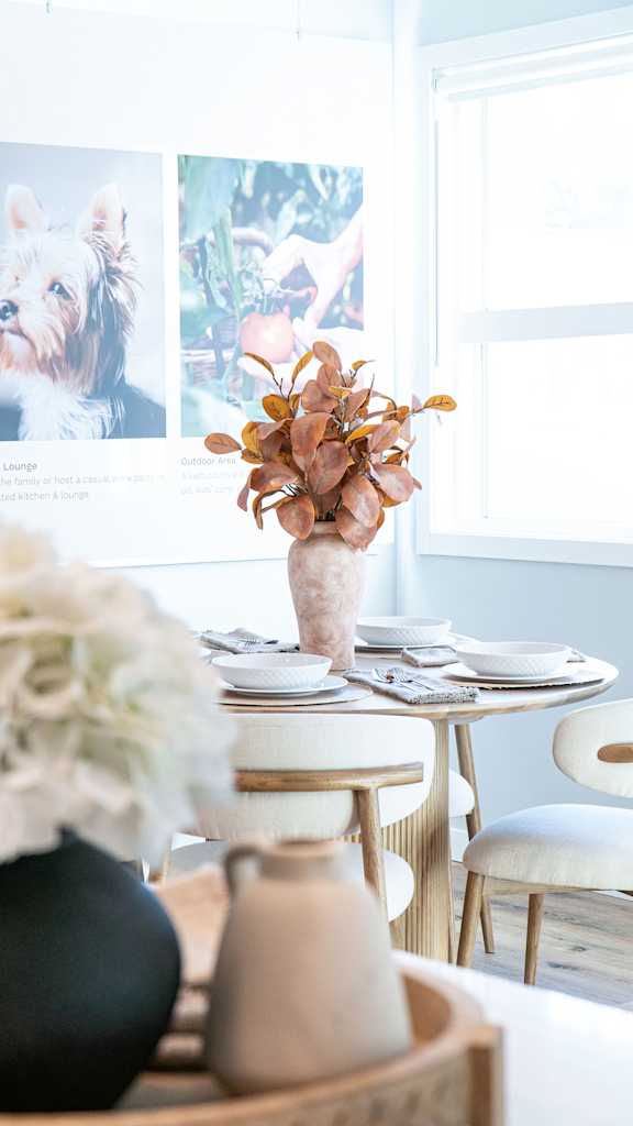 A dining table with a vase of flowers on it.