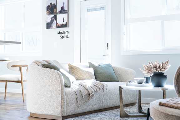 A white couch with pillows and a blanket on it.