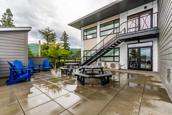 a patio with chairs and tables and a building with a staircase