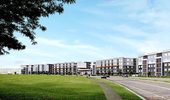 A row of modern apartment buildings with a green lawn in front.