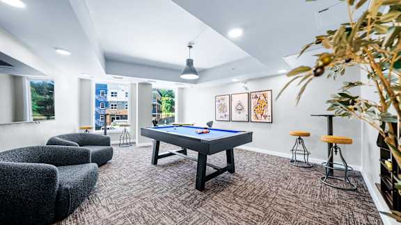 A room with a pool table and bar stools.