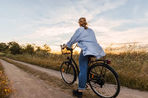 a woman riding a bike down a dirt road