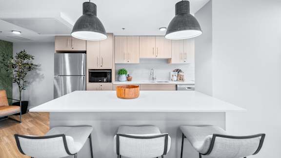 A modern kitchen with a white table and grey chairs.