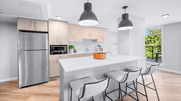 A modern kitchen with a white countertop and grey bar stools.