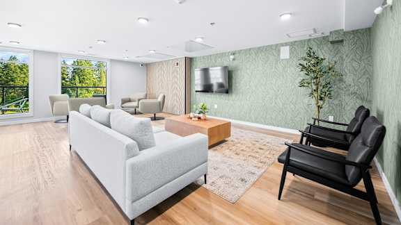 A living room with a grey couch, a black chair, and a wooden coffee table.