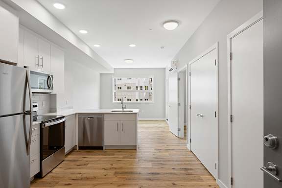 A modern kitchen with wooden floors and white cabinetry.