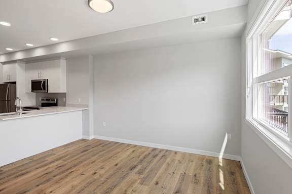 A kitchen with a white counter and wooden flooring.