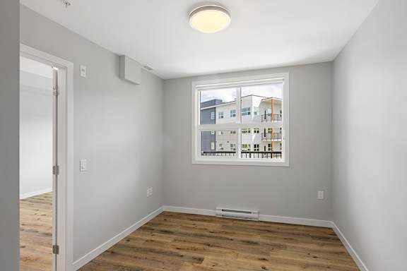 A room with a window showing a view of buildings outside.