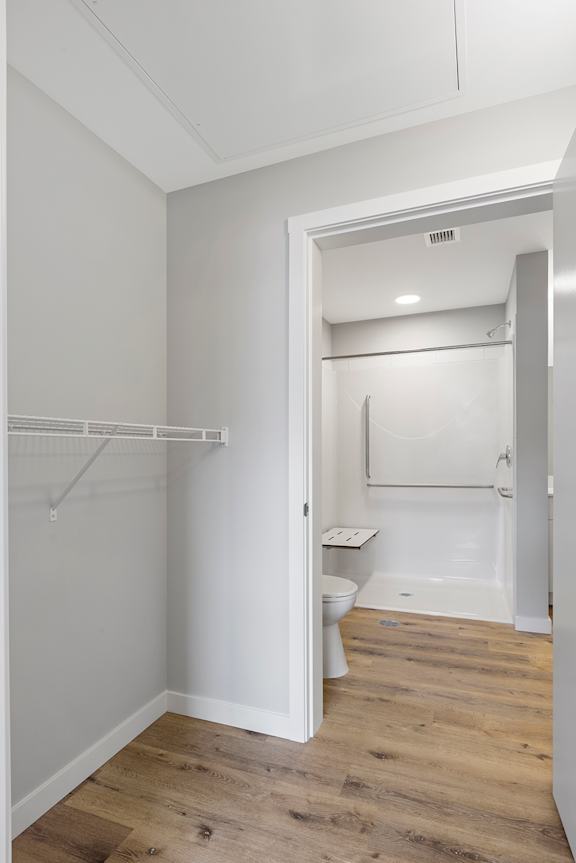 A white bathroom with a toilet and a walk-in shower.