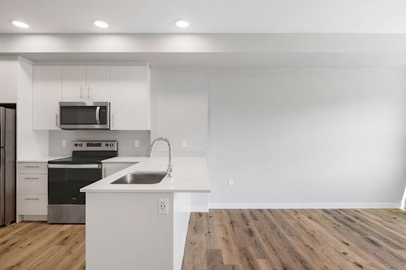A modern kitchen with a white countertop and stainless steel appliances.