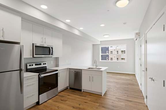 A modern kitchen with wooden floors and white cabinetry.