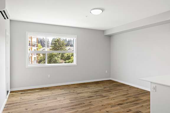 A room with a large window and wooden flooring.