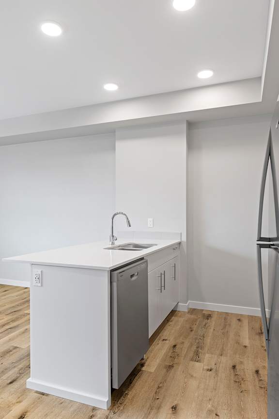 A kitchen with a white countertop and a white dishwasher.
