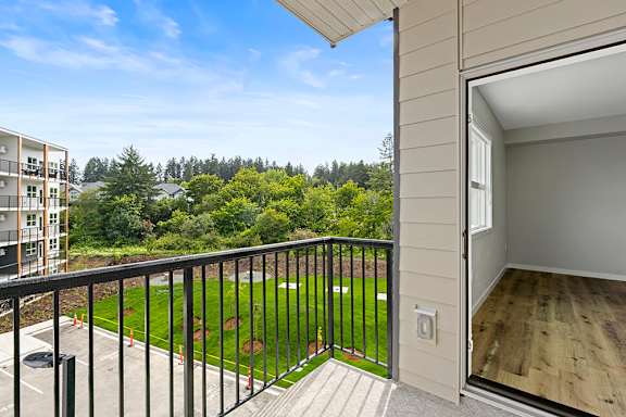 A balcony with a view of a green field and trees.