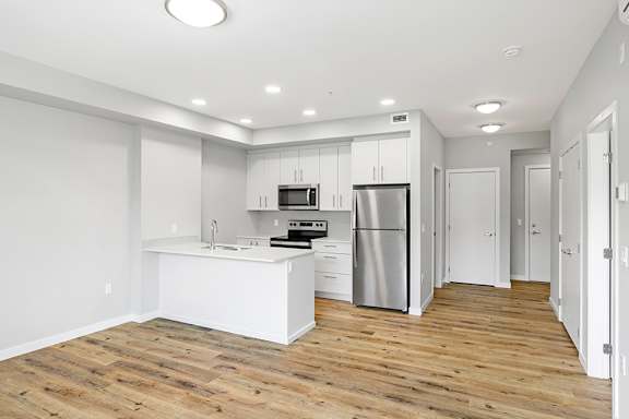 A kitchen with a refrigerator, sink, and cabinets.