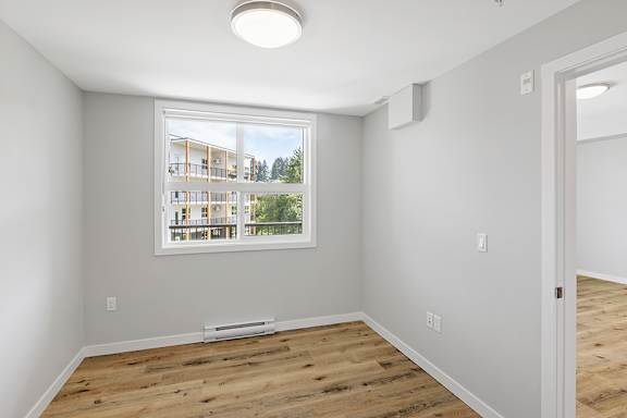 A room with a large window and wooden flooring.