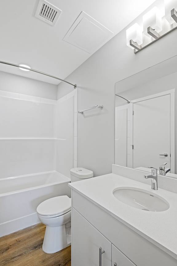 A white bathroom with a toilet, sink, and mirror.