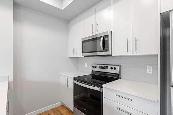 A kitchen with white cabinets and a black stove top oven.