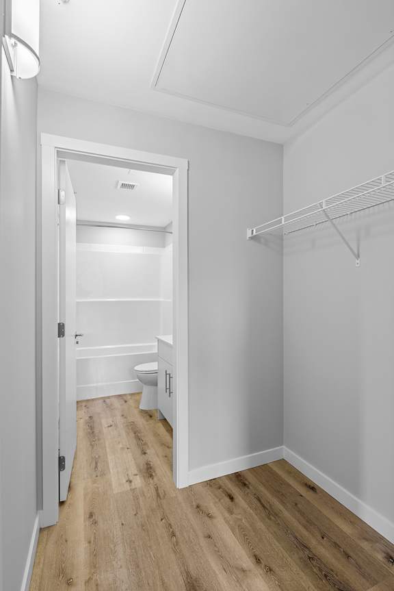 A white bathroom with wood flooring and a white door.