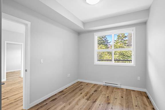 A room with a window that has a view of trees and a house.