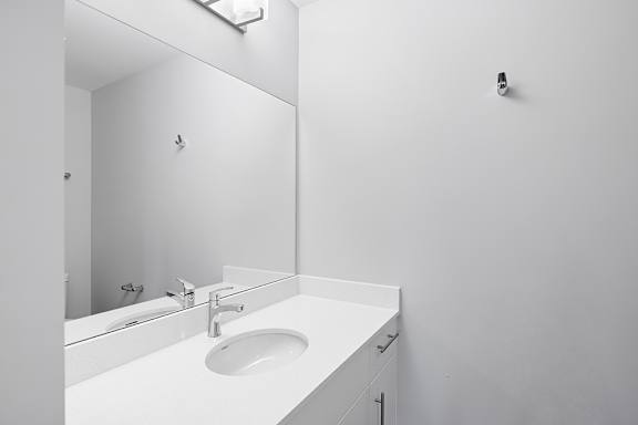 A white sink in a bathroom with a mirror above it.