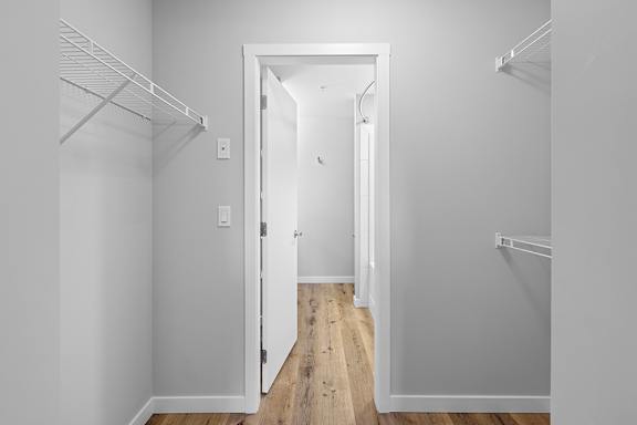 A white hallway with a doorway leading to another room.